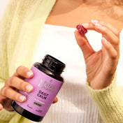 Person holding Upstate Elevator Daily Calm CBD gummy bottle and picking up a single mixed fruit gummy