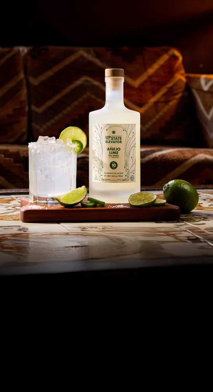 Anejo Lime spirit bottle with a cocktail and limes on a wooden surface